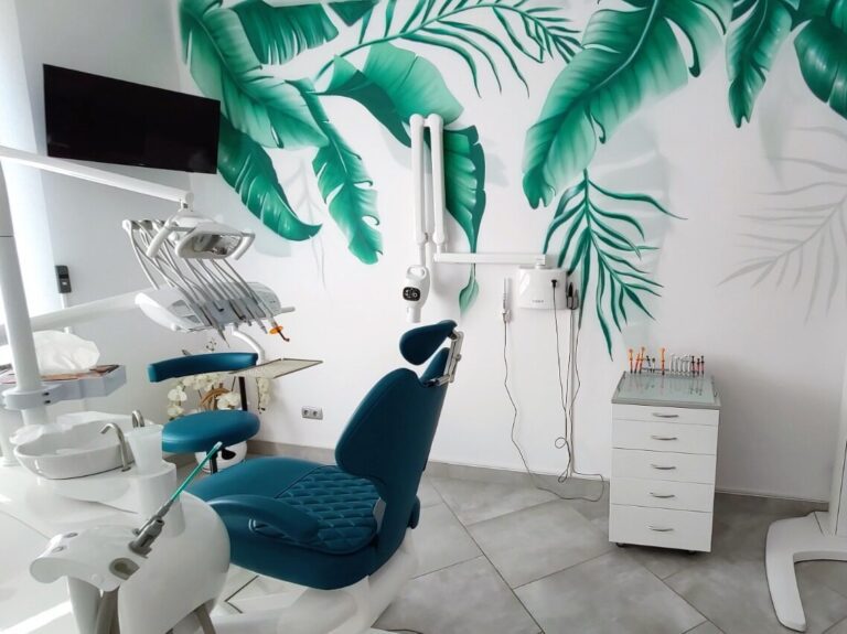 Gabinet stomatologiczny z turkusowym fotelem w tle liście namalowane na ścianie